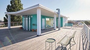 Une terrasse sur le toit avec un espace salon couvert, des plantes en pot et une vue sur la ville.
