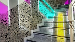 Un escalier avec un mur décoré de mosaïques et une main courante.