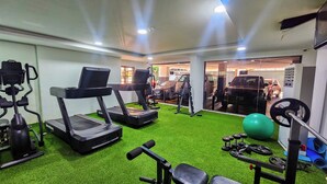 Une salle de sport équipée de tapis de course, d’appareils de musculation et de ballons d’exercice.