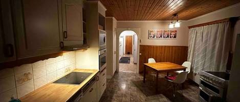 Una cocina compacta con armarios de madera, una isla central y un comedor con mesa y sillas.