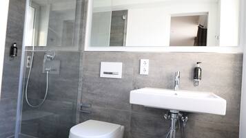 Une salle de bain moderne avec une douche à parois de verre, un lavabo blanc et des toilettes.