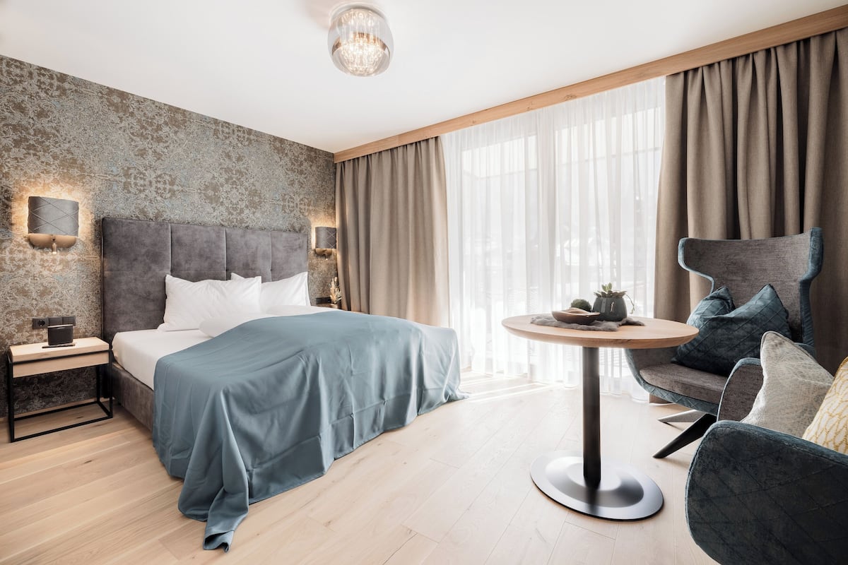 Una habitació d'hotel moderna amb un llit gran, una taula rodona i un butac armchair còmode.