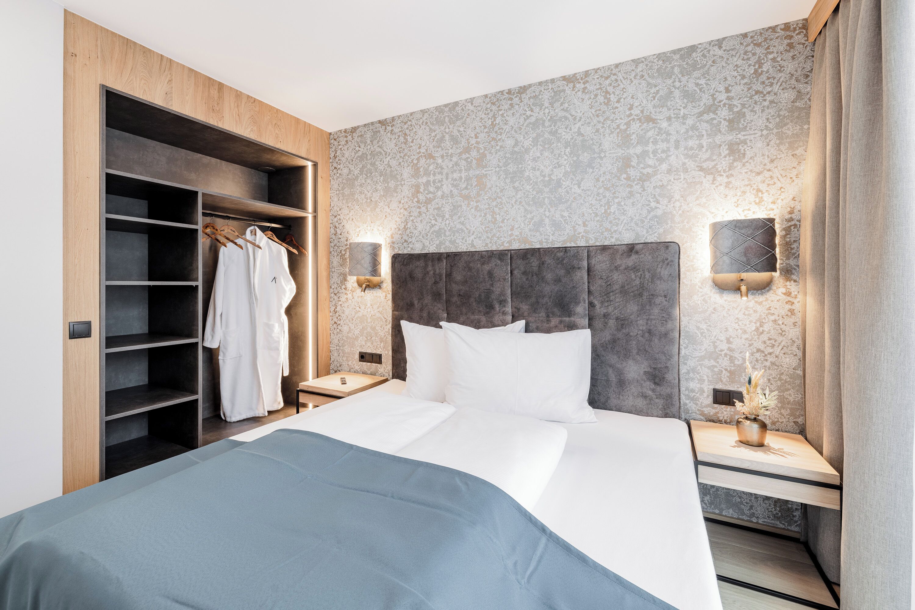 Ein modernes Hotelzimmer mit einem großen Bett, einem Holzschrank und einem Nachttisch mit Lampe.