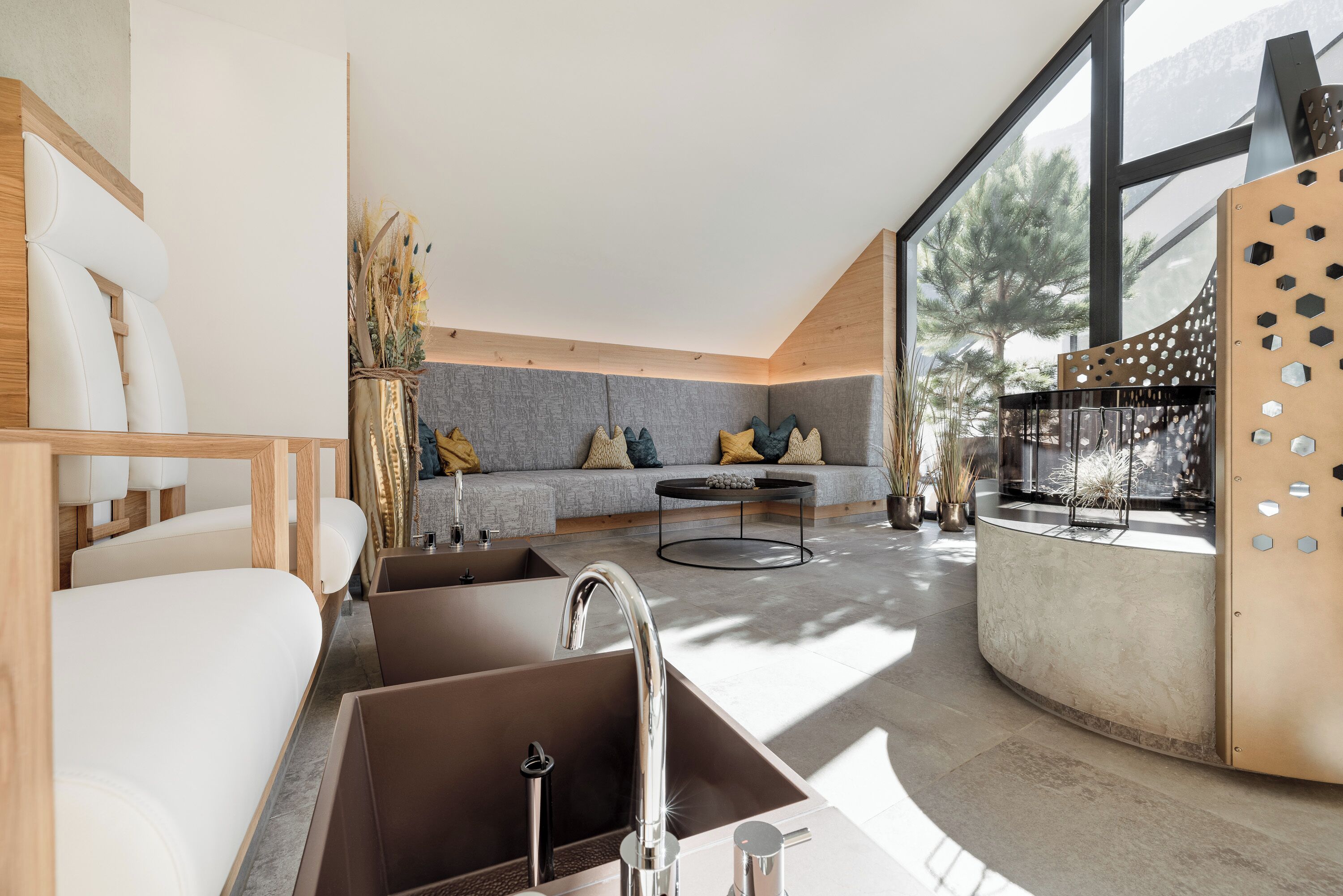 A modern kitchen with a built-in sink, a dining area with a round table, and a seating area with a sofa and cushions.