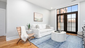 A modern living room with a white sofa, a round coffee table, and a blue patterned rug. - Lavish Apartment over Target in Downtown Auburn - 205 (Auburn)