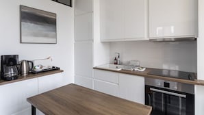 A modern kitchen with white cabinets, a stainless steel range hood, and a wooden countertop.
