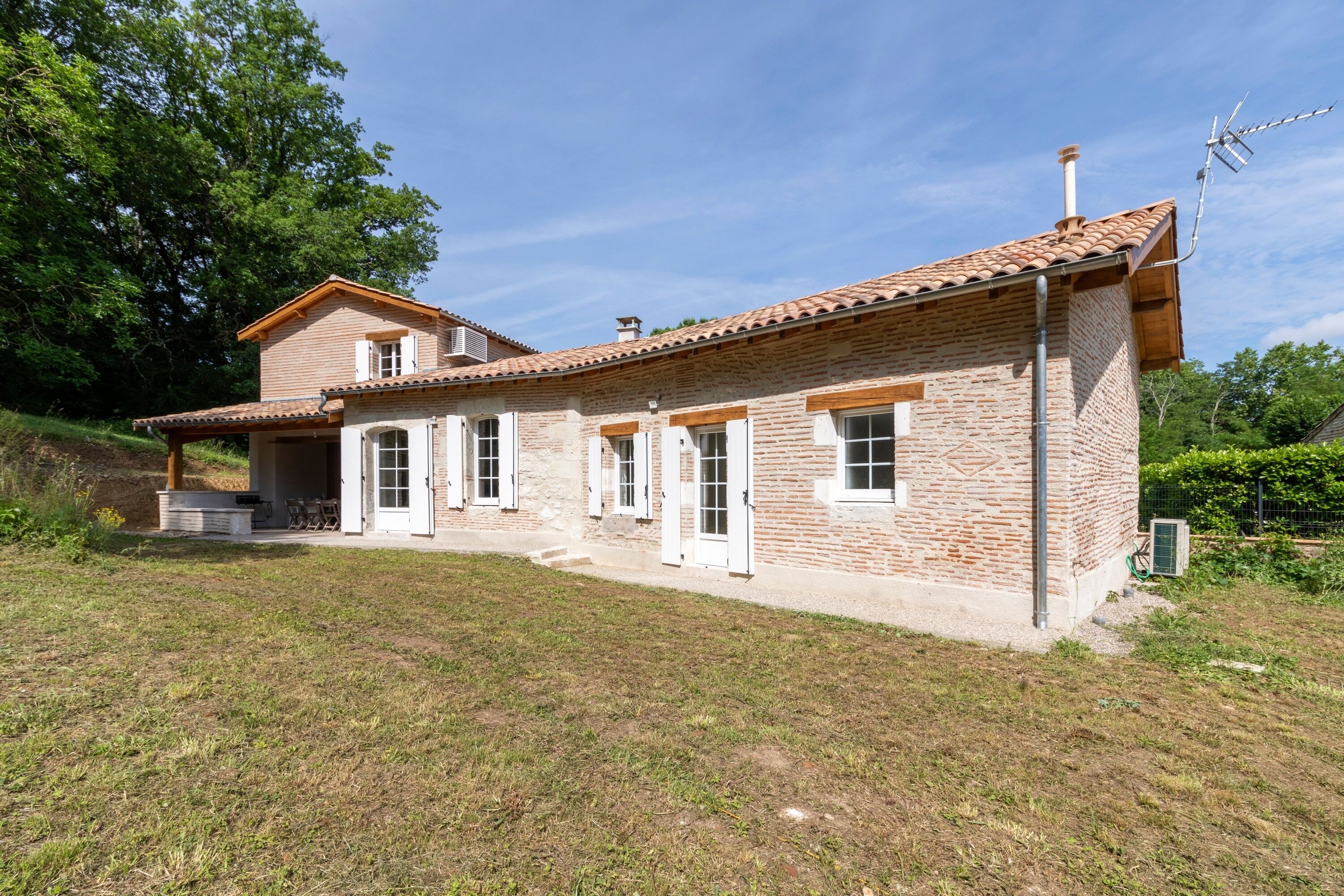 Una casa de dos pisos con techo de tejas, paredes de ladrillo y un pequeño porche.