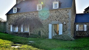 Ein Haus aus Stein mit einem geneigten Dach, einem Schornstein und einem kleinen Fenster im zweiten Stock.