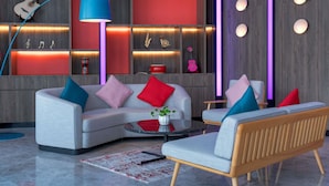 Een moderne woonkamer met een grijze bank, kleurrijke kussens, een ronde salontafel en een houten bijzettafeltje.