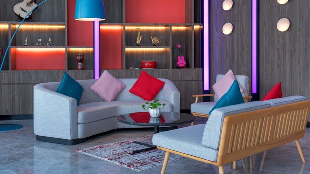 Een moderne woonkamer met een grijze bank, kleurrijke kussens, een ronde salontafel en een houten bijzettafeltje.