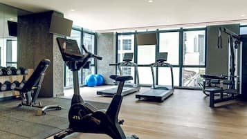 Un gimnasio con máquinas de cardio, mancuernas y pelotas de ejercicio.