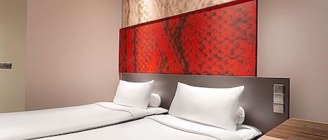 A hotel room with two beds, a wooden nightstand, and a marble wall with a red floral pattern.