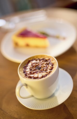 A cup of coffee with a frothy top on a saucer, placed on a wooden table. - Ibis Istanbul Airport (Arnavutköy)