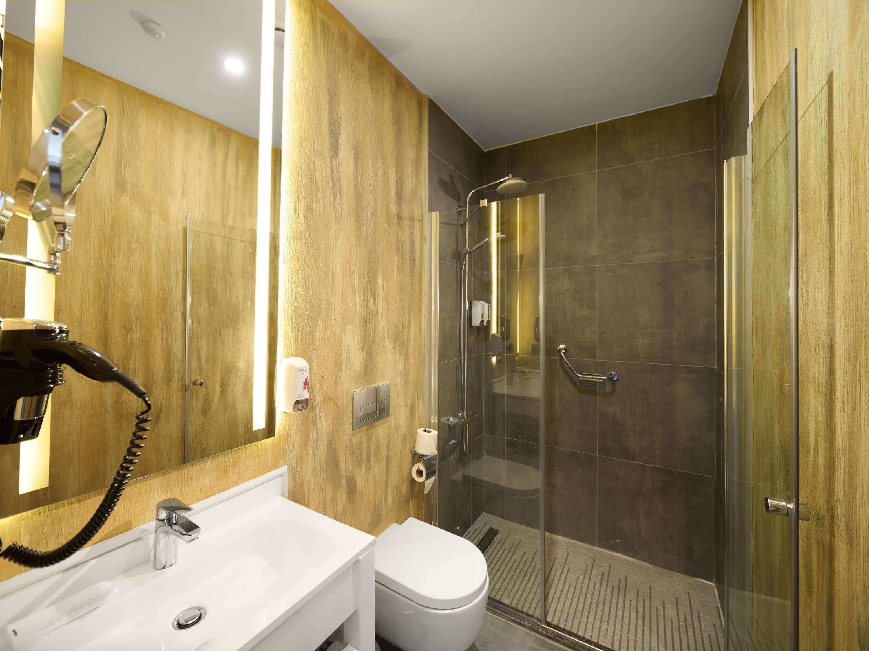 A modern bathroom with a glass-enclosed shower, a white sink, and a toilet.