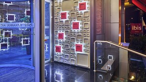 A hotel lobby with a modern design, featuring a patterned wall, a staircase, and a glass entrance. - Ibis Istanbul Airport (Arnavutköy)