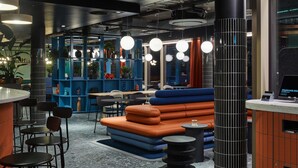A modern interior with seating areas, tables, and a registration counter. - TRIBE Baden-Baden (Baden-Baden)