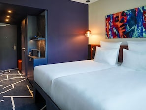 A hotel room with a bed, a nightstand, a painting, and a door leading to a bathroom. - TRIBE Baden-Baden (Baden-Baden)