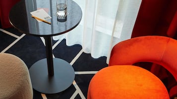Ein modernes Hotelzimmer mit rundem Tisch, einem Glas Wasser und einem Notizblock.
