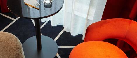 A modern hotel room with a round table, a glass of water, and a notepad.