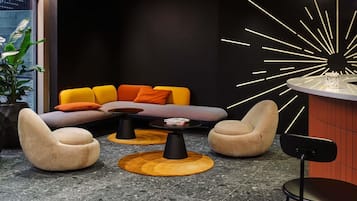 Een moderne zithoek met een modulaire bank, twee fauteuils, een salontafel en een opvallend kunstwerk aan de muur.