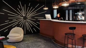 Un área de bar moderna con una barra curva, taburetes, una zona de estar circular y un diseño de iluminación de pared original.