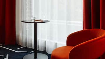 Ein Zimmer mit einem runden Tisch, einem Stuhl und Blick durch transparente Vorhänge.