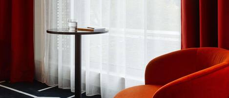 Una habitación con una mesa redonda, una silla y vistas a través de cortinas translúcidas.