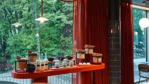 A modern interior with a dining area, a red accent wall, and a view of greenery outside.