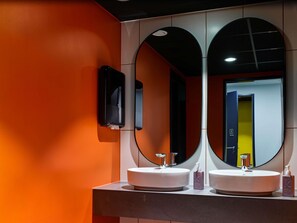 A modern bathroom with two sinks, a mirror, and a soap dispenser. - TRIBE Baden-Baden (Baden-Baden)