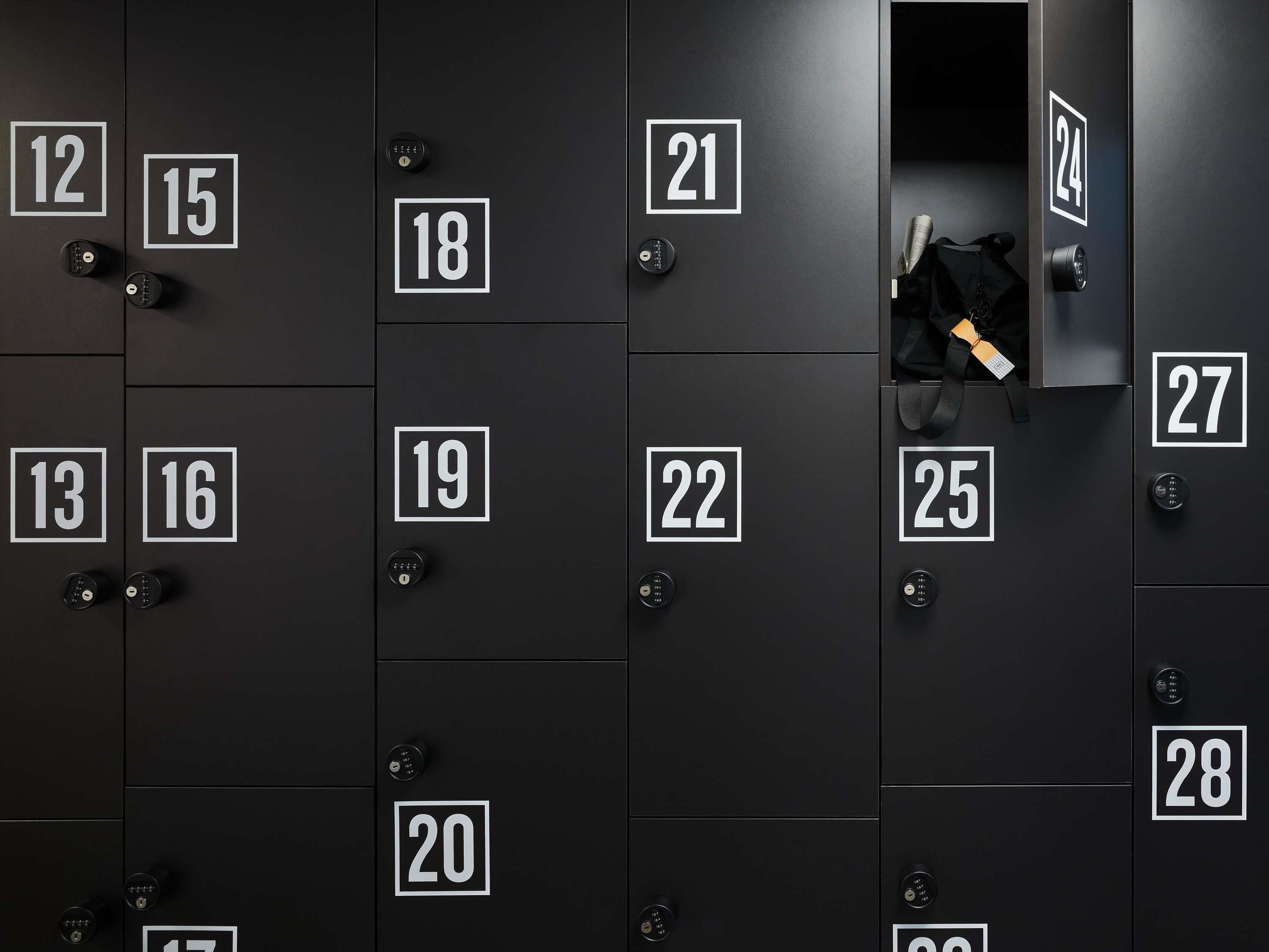 A row of black lockers with white numbers, each with a keyhole.