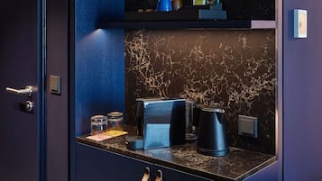 Eine moderne Küche mit Marmor-Spritzschutz, einer Kaffeemaschine, einem Wasserkocher und einem kleinen Regal mit Gegenständen.