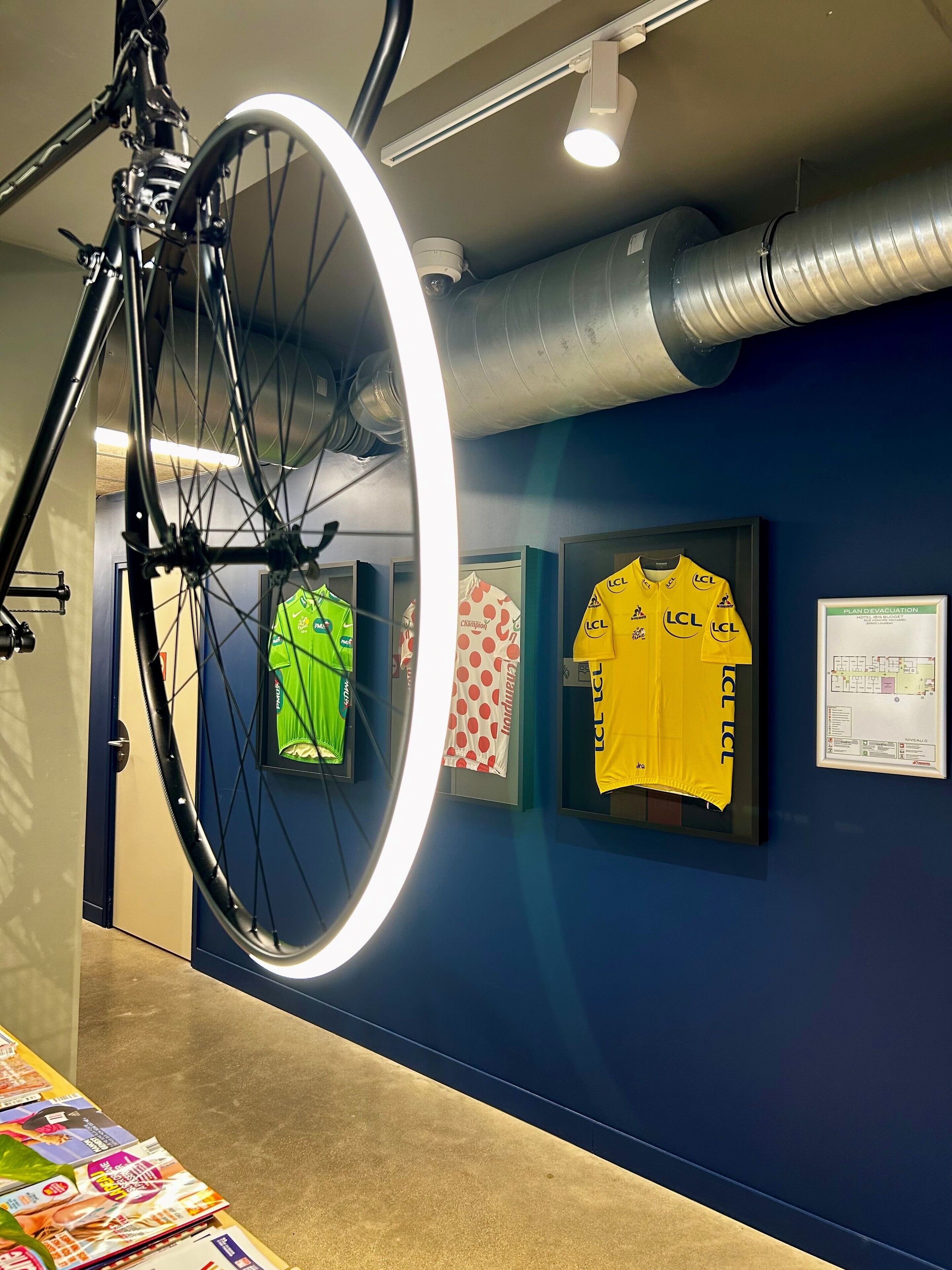 Uma bicicleta com uma roda dianteira, uma camisa emoldurada e um plano de evacuação emoldurado na parede.