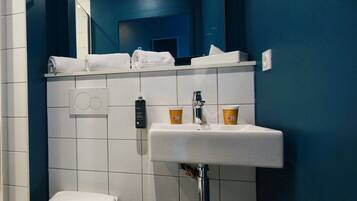 Un baño con inodoro blanco, lavabo con espejo y pared azul.
