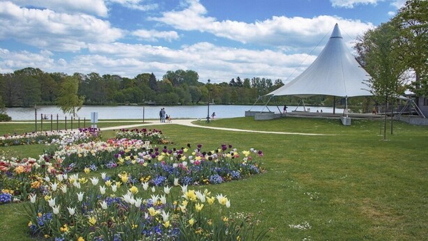 A park with a lake, a pavilion, and a flower garden.