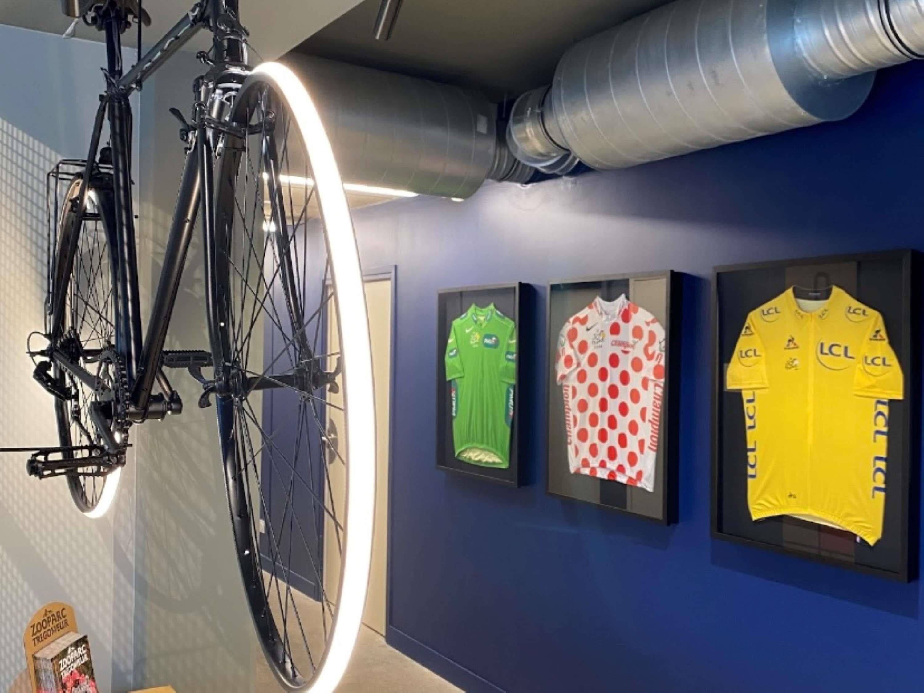 Een fiets, drie truien en een muur met een ronde lamp.