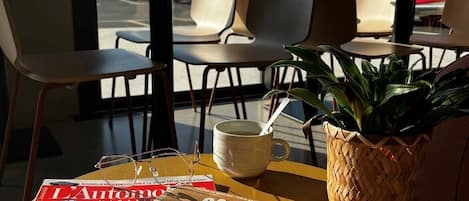 Una mesa con una revista, una taza y una planta.