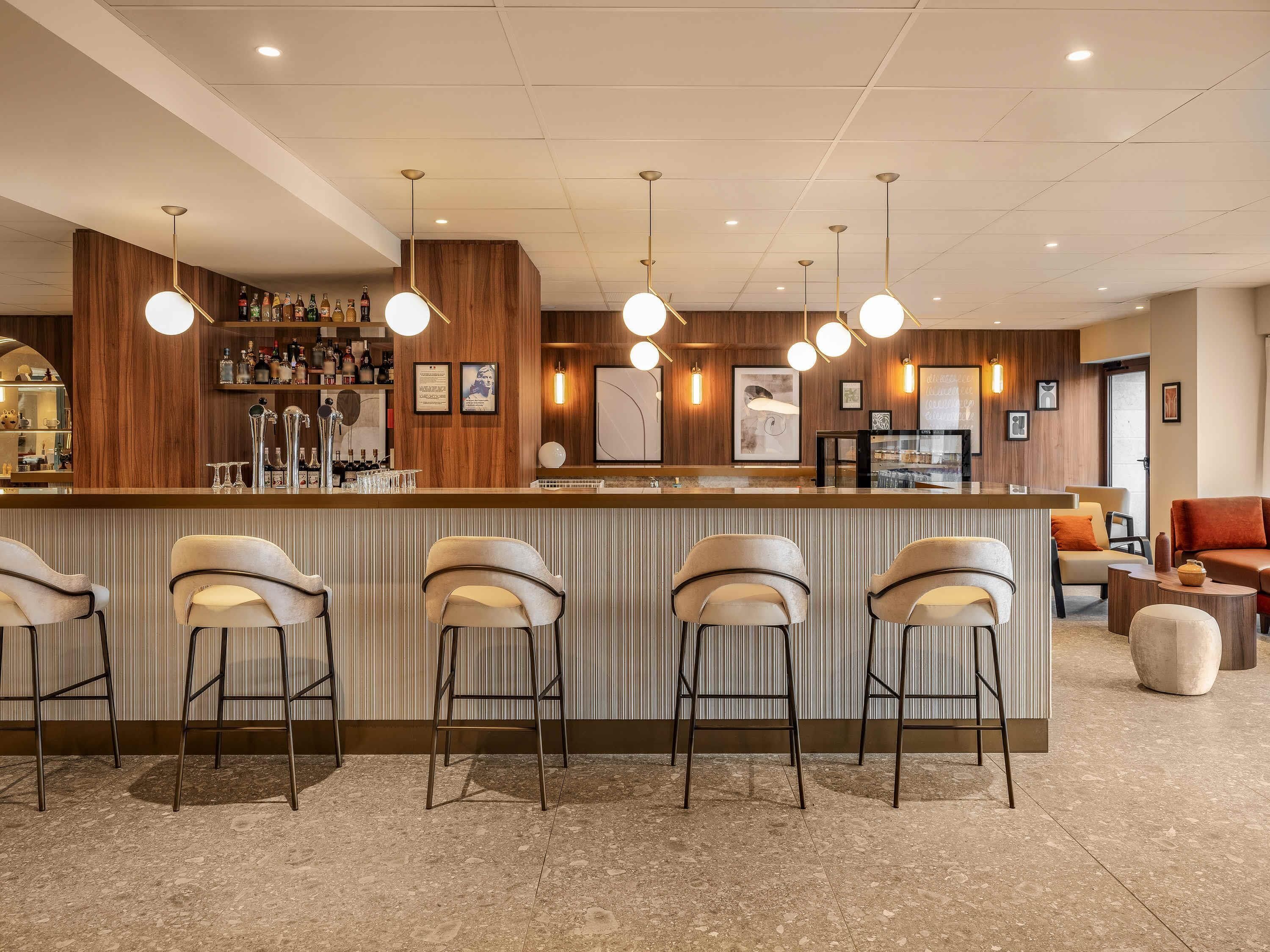 A bar area with a counter, bar stools, and a selection of bottles.