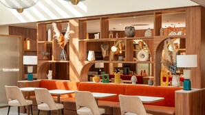 A modern interior with wooden shelving, a red sofa, and multiple tables and chairs.