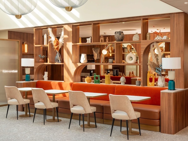 Un interior moderno con estanterías de madera, un sofá rojo y varias mesas y sillas.