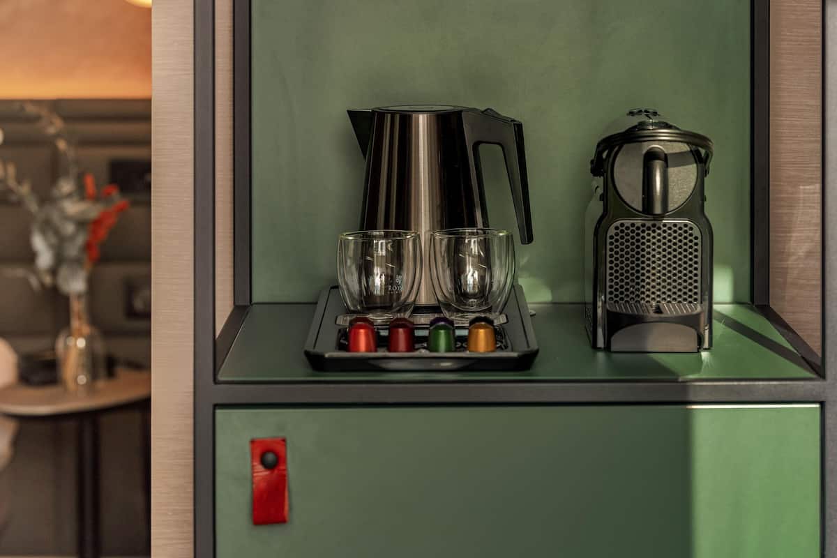 Une petite cuisine équipée d’une machine à café, de deux verres et d’une râpe.
