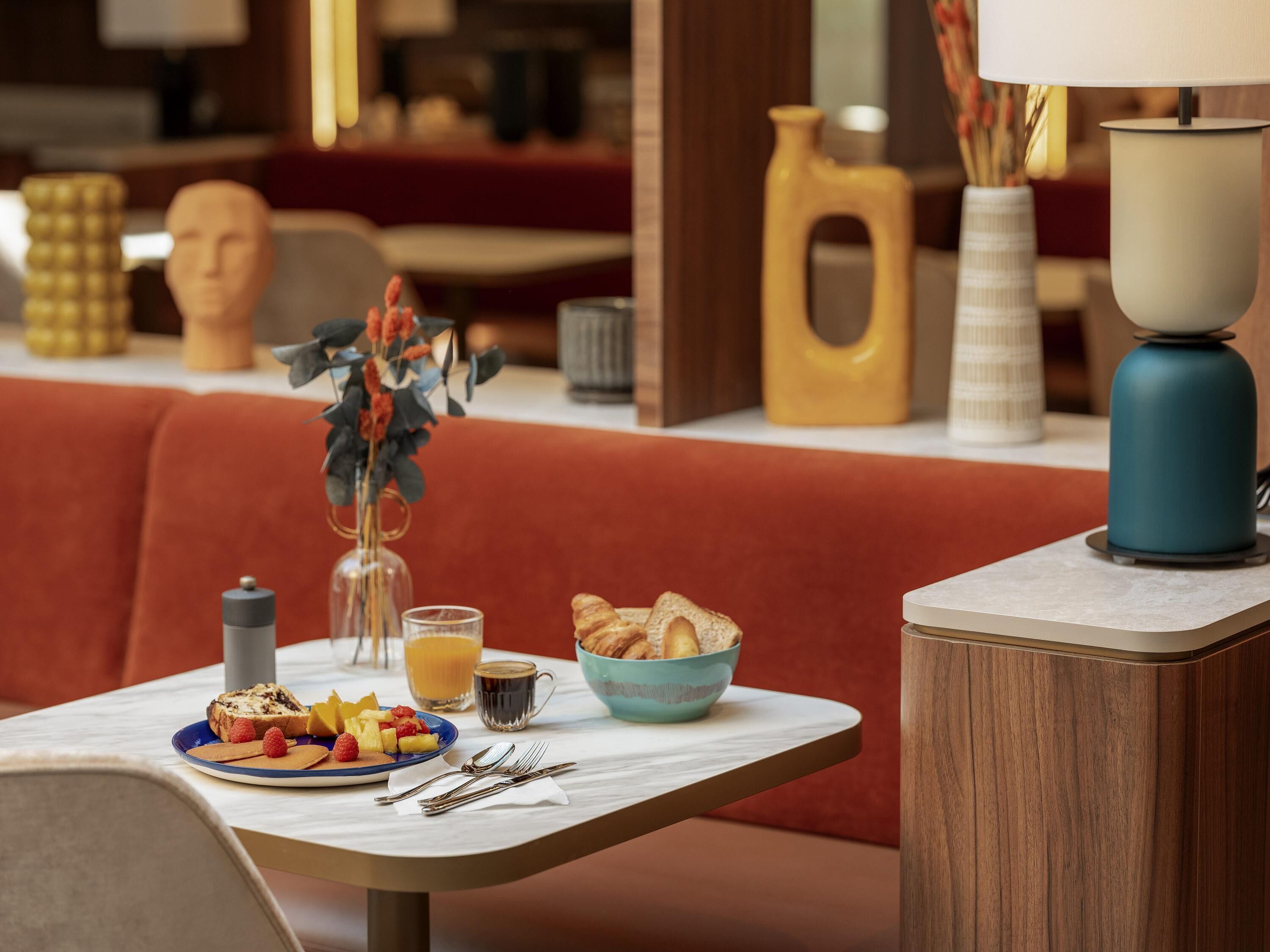 A breakfast setting with a plate of toast, fruits, and a coffee cup on a marble table.