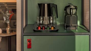 A kitchenette with a coffee maker, two glasses, and a grater.