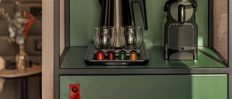 Una kitchenette con cafetera, dos vasos y un rallador.