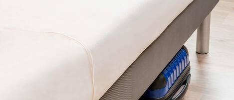 A bed with a mattress and a grey underbed storage compartment.