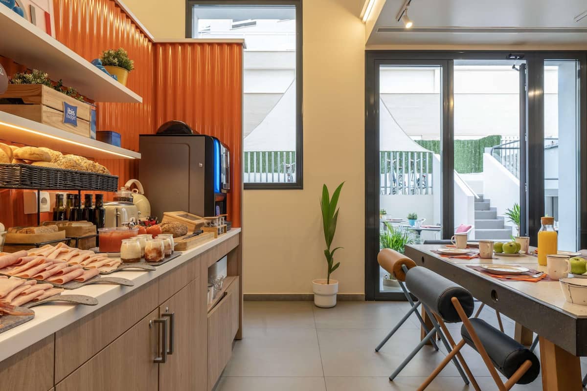 Una cocina moderna con barra americana, armarios de madera y vista al balcón exterior.