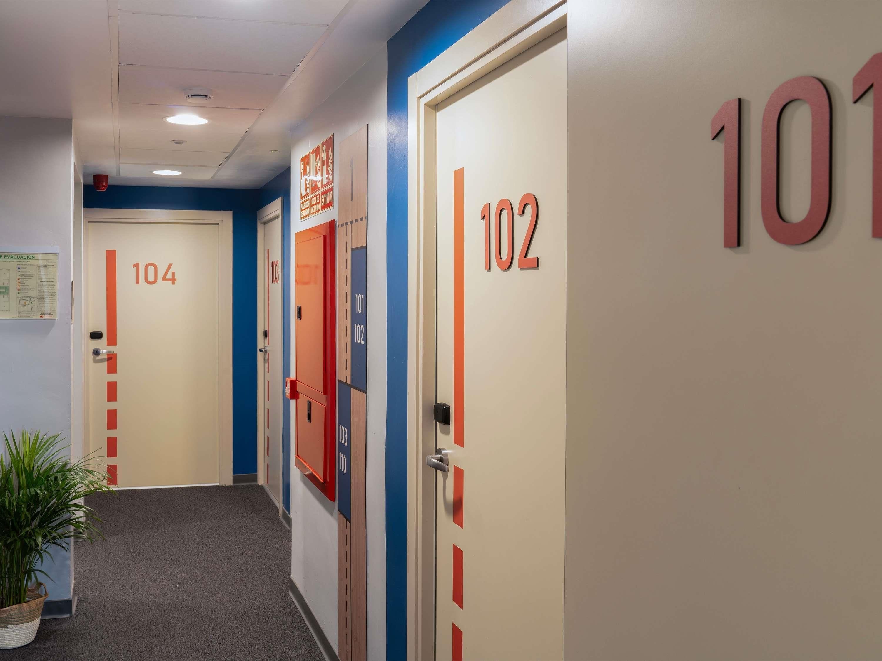 A hotel corridor with doors numbered 101, 102, and 104, each with a red stripe.