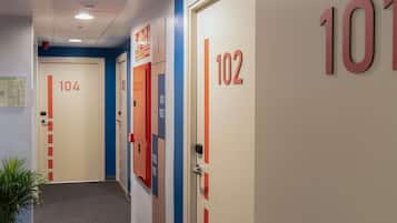 Un pasillo de hotel con puertas numeradas 101, 102 y 104, cada una con una franja roja.