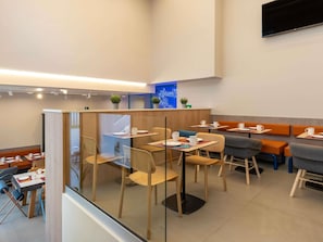 A modern cafe with glass partitions, wooden tables, and comfortable seating. - Ibis Budget Valencia Centro Puerto (Valencia)