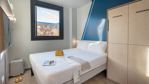 A hotel room with a bed, a window with a view, a wardrobe, and a radiator. - Ibis Budget Valencia Centro Puerto (Valencia)