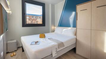 Une chambre d’hôtel avec un lit, une fenêtre donnant sur un paysage agréable, une armoire et un radiateur.